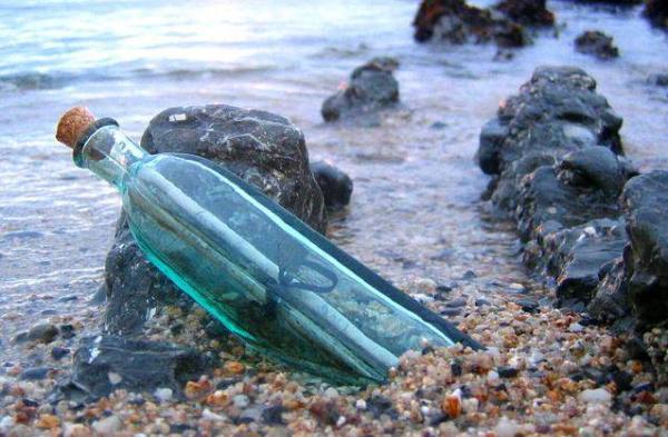 bottiglia con pergamena tra pietre in riva